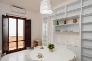 a white dining room with a white table and a window at San Menaio Apartment by Rentbeat in San Menaio