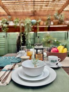 a table with plates and cups and a bowl of fruit at Fig Tree Rock 2-bed, 2-bath villa with garden and parking in Nelspruit