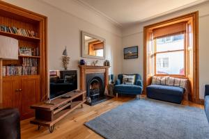 a living room with a fireplace and blue chairs at Dylsford - Elie in Elie