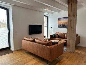a living room with two brown couches and a tv at Van Senden 8 Elsje in Krummhörn