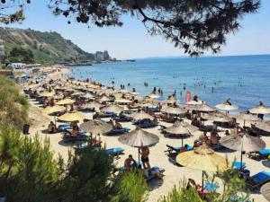 a group of people sitting on a beach with umbrellas at Sea View Apartment in Durrës