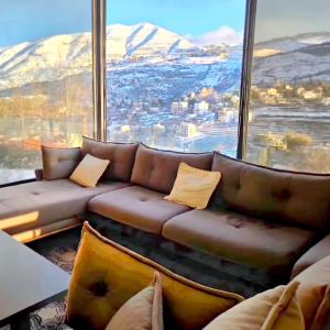 a living room with a couch in front of a large window at Farayayellowstone 1 bedroom with panoramic mountain view fit 4 in Bayn an Nuhūr