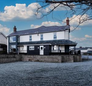 a white house with a black roof at Glan Neigr Apart-Hotel by Guestz in Rhosneigr