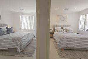 two beds in a bedroom with white walls and windows at Shipwreck Park Villas in Westfield