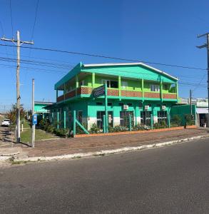 a green building on the side of a street at Pousada Azambuja in Cidreira