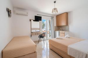 a bedroom with two beds and a kitchen with a window at Katerina View in Mikonos