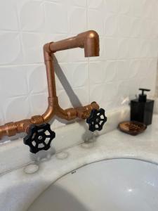 a bathroom sink with a copper faucet at Chalé Mi casa Su casa in Itamonte +30 photos