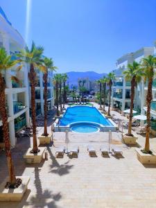 a resort with a pool and palm trees and buildings at Orins place eilat in Eilat