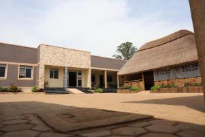 a building with a thatched roof and a courtyard at Simbego Cottages Lira in Lira