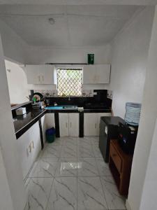 a kitchen with white cabinets and a tile floor at Malindi Jerere BnB in Malindi