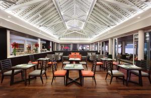 a restaurant with tables and chairs and windows at Amari Phuket in Patong Beach
