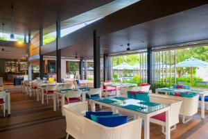 ein Restaurant mit Tischen, Stühlen und Fenstern in der Unterkunft OZO Phuket in Kata Beach