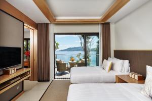 a hotel room with two beds and a television at Amari Phuket in Patong Beach