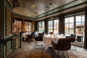 a dining room with tables and chairs and windows at Romantik Hotel Schweizerhof in Grindelwald