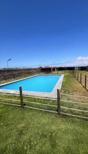 a swimming pool with a fence in the grass at Refugio El Tatán in Choros Bajos