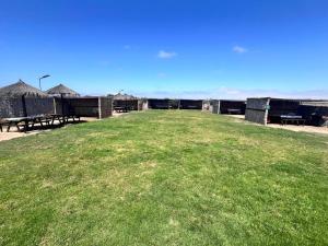 a large grassy area with tables and benches in a field at Refugio El Tatán in Choros Bajos