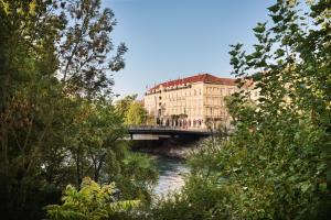 a bridge over a river with buildings and trees at Hotel Weitzer Graz - Centre of Graz in Graz