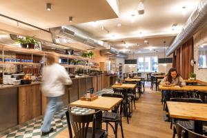 two people sitting at tables in a restaurant at MEININGER Hotel Berlin Mitte in Berlin