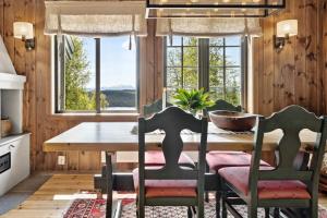 a dining room with a table and chairs and windows at Mountain Cabin With Great Views in Austbygdi