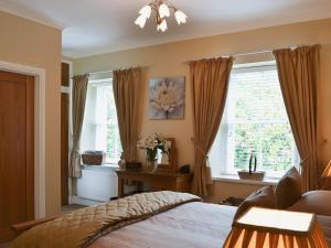 a bedroom with a bed and two windows at Ladybird Cottage in Lochend +12 photos