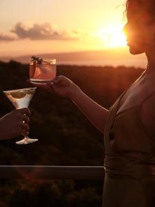 a woman holding a drink with the sunset in the background at Searocks Exclusive Village in Kalamata +53 photos