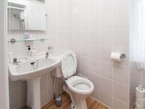 a white bathroom with a toilet and a sink at Rosaire Guest House in Llandudno