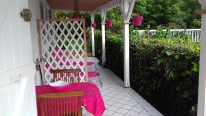 a porch with two chairs and a table with a pink blanket at Meridienne Creole in Sainte-Anne