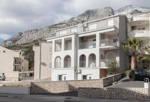 a white building with a mountain in the background at Villa Klara Guest House in Baška Voda