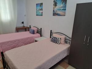 a bedroom with two beds with pink sheets and a cabinet at Belle maison in Goodlands