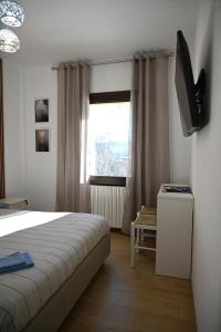 a bedroom with a bed and a television and a window at Ca' Tra Cielo e Monti in Frassinoro