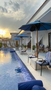 a pool with chairs and umbrellas next to a building at Santai Suites Nusa Dua in Nusa Dua
