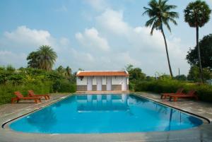 a swimming pool with two chairs and a building at The Mountain Retreat in Tiruvannāmalai