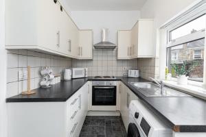 a kitchen with white cabinets and a black counter top at The Cosy Durham Nest in Langley Park