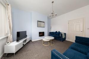 a living room with a blue couch and a tv at The Cosy Durham Nest in Langley Park