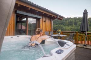 a woman sitting in a hot tub on a deck at Bergdorf Spessart in Flörsbachtal