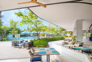 a restaurant with tables and chairs and a pool at OZO North Pattaya in Pattaya