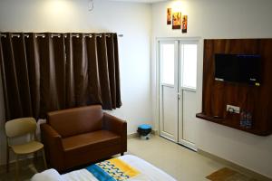 a room with a chair and a tv and a window at Hotel Parineeta in Khagaria