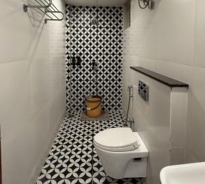 a bathroom with a toilet and a black and white tile floor at Hotel La Hotera in Hyderabad