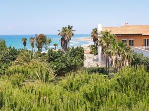 a view of the beach from a house with palm trees at Mandola Rosa, A Resort to Live in Loutra Killinis