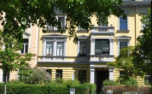 ein gelbes Gebäude mit vielen Fenstern in der Unterkunft Ferienwohnung im Univiertel mit Garten in Graz