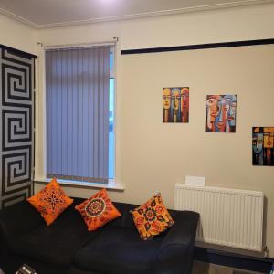 a living room with a black couch with orange pillows at Ince House in Liverpool