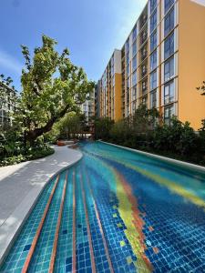 a pool with a rainbow in the water next to a building at Rest&Rise Phuket in Ban Rangeng