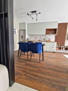 a kitchen with a dining table and blue chairs at By The Pool Apartments #7 in Velingrad