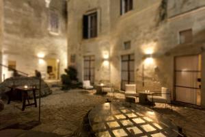 un bâtiment avec une table et des chaises en verre dans une cour dans l'établissement Corte San Pietro, à Matera