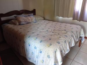 a bed with a floral comforter in a bedroom at Casa 4 Quartos garagem 3 carros, churrasqueira e ar condicionado, in São José
