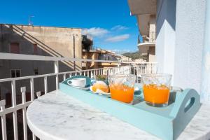a tray with two glasses of orange juice on a balcony at Hotel Villa Nefele in Giardini Naxos