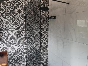 a shower with a black and white tile wall at Boh- House in Graskop +29 photos