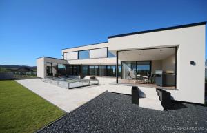 a large white house with a patio and grass at Eifelvilla Weber in Arenrath
