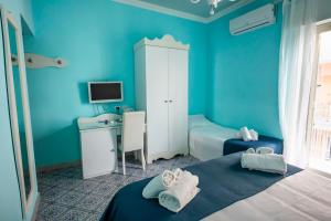 a blue room with two beds and a desk at Hotel Villa Nefele in Giardini Naxos