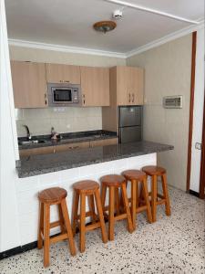a kitchen with four wooden stools next to a counter at Los Ficus in Playa del Ingles